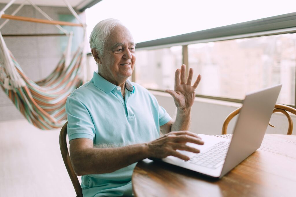 Cette photo montre un homme Ã¢gÃ© faisant signe de la main Ã  l'ordinateur devant. Elle dÃ©montre que les sites internet doivent Ãªtre accessibles pour tout type de public (dont les personnes Ã¢gÃ©es).