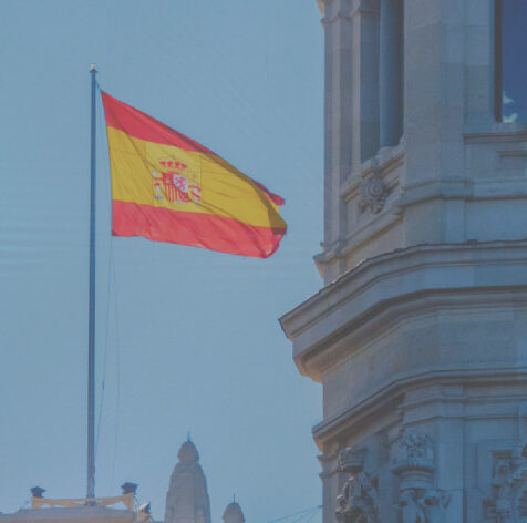 Drapeau espagnol flottant devant un bÃ¢timent historique, symbolisant la formation en Espagnol certifiÃ©e LILATE Ã  Cambrai