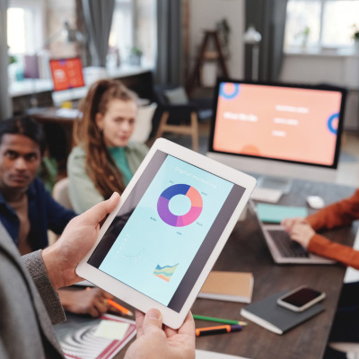 Session de formation sur les compétences digitales montrant un participant présentant des statistiques sur une tablette devant un groupe de collègues